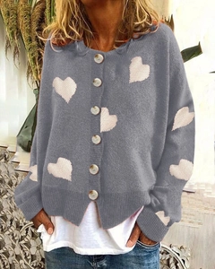 Detail of grey knitted cardigan with white heart patterns and round front buttons
