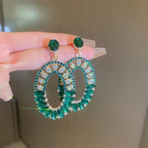 Luxurious geometric oval earrings with emerald green crystals and white diamonds in gold