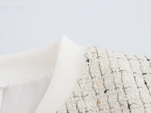 Détails de la veste blanche en tweed montrant le col en maille et les fils dorés
