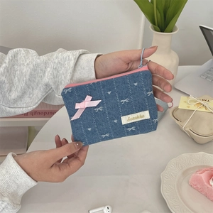 Dettaglio del portamonete in denim con ricamo a fiocco e cerniera rosa