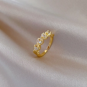 Macro shot of gold heart ring with pavé zircons on champagne satin background