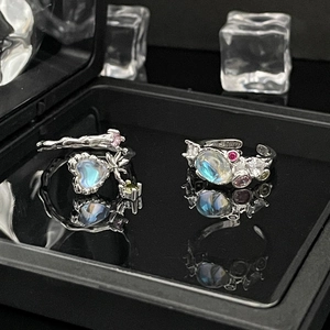 Detailed macro view of silver open rings with colorful heart and oval moonstones on black