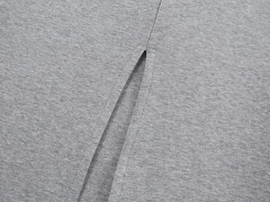 Macro detail of high-quality grey knit fabric with durable double-stitched hem and slit
