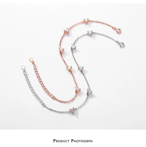 Détail de bracelets en argent et or rose avec incrustations d'opale en cœur et chaînettes