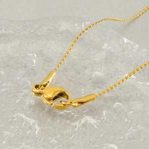 Macro detail of a gold stainless steel necklace lobster clasp on a water drop surface