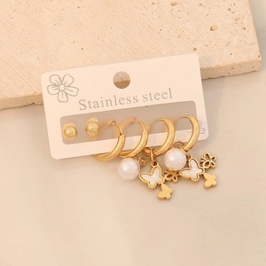 Détail de boucles d'oreilles en acier doré avec pendentifs papillon et perles