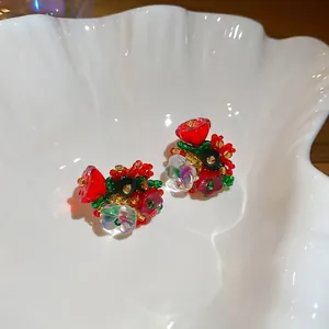 Elegant floral beaded stud earrings with iridescent petals on a white shell tray