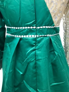 Detail of emerald green fishtail evening gown with gold sequins and white waist embroidery