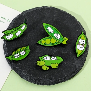 Close-up of five creative pea-pod cat enamel pins on a black stone coaster background