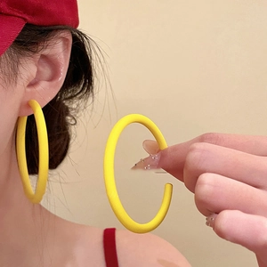 Close-up of model wearing large yellow acrylic hoop earrings with a cream summer aesthetic