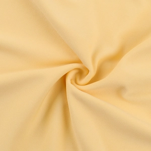 Macro detail of soft beige ruched fabric showing fine knitted texture and elegant drape