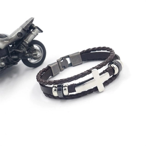 Close-up of multilayer brown leather bracelet featuring a silver cross charm and metal beads