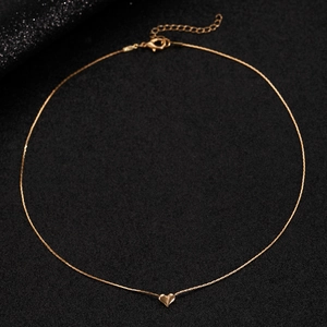 Detail of gold heart pendant necklace with lobster clasp on a black textured background