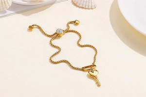 Détail d'un bracelet doré ajustable avec pendentif clé en cœur et fermoir coulissant élégant