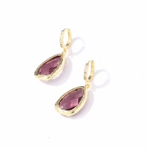 Détail de boucles d'oreilles dorées avec cristaux violets et oxydes de zirconium