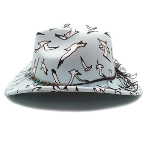 Detail of light blue felt cowboy hat with white bird prints and beaded tassels