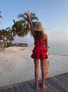 Rear view of woman in red ruffled lace two-piece set on tropical beach at sunset