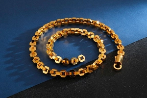 Close-up of golden stainless steel hip hop chain with hexagon links on blue background