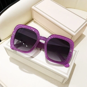 Detailed shot of purple glitter square sunglasses with gradient lenses on gift boxes