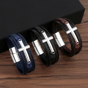 Detailed view of multilayer leather bracelets with metallic cross charms on wood surface