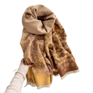 Leaf pattern scarf in brown and yellow with fringe tassels shown on white background