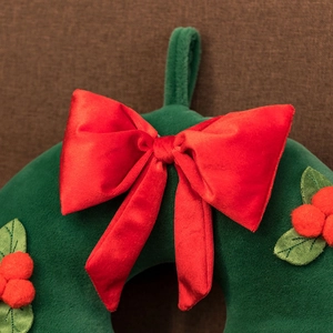 Close-up of plush green Christmas wreath with a large red velvet bow and berry details