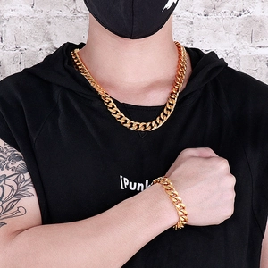 Close-up of a model wearing an 18K gold cuban link necklace and matching bracelet set