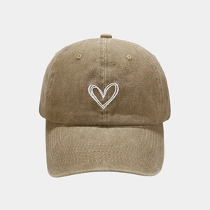 Detail of vintage washed khaki baseball cap featuring minimalist heart embroidery