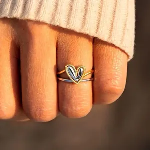 Minimalist heart-shaped ring set in gold and silver finish worn by a model