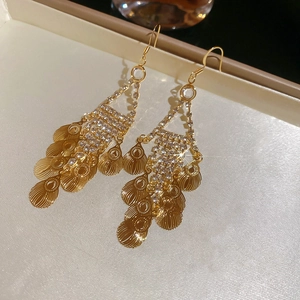 Detail of vintage gold leaf tassel earrings with sparkling rhinestones and layered metal scales