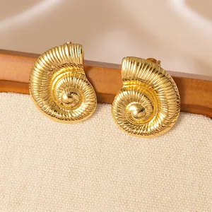 Close-up of golden nautilus shell earrings with intricate spiral texture details