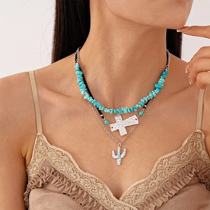 Close-up of bohemian layered necklace with turquoise stones, cross and cactus pendants