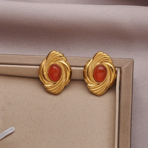 Detail view of gold twisted oval earrings with orange turquoise stone in jewelry box