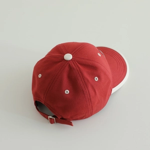 Detail of red kids baseball cap with white piping and adjustable metal buckle