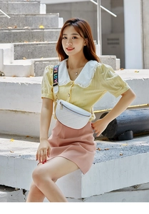 Detail of white quilted belt bag with gold zippers and colorful LOVE strap on model