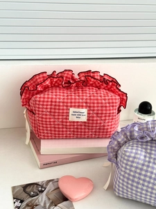 Detail of berry gingham makeup bag with ruffle edges and woven brand label