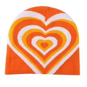 Detailed knit texture of orange and yellow heart pattern beanie with white accents