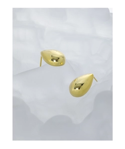 Macro shot of minimalist golden teardrop stud earrings with polished mirror finish