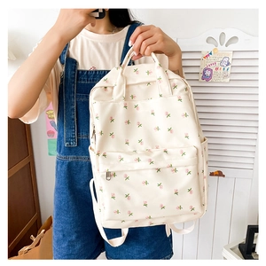 Detailed view of beige floral canvas backpack with front pocket and zipper closure