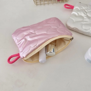 Detail of pink quilted cosmetic bag with heart patterns and soft zipper puller