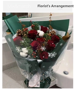 Close-up of Christmas bouquet with red roses and pine cones in snowflake wrapping paper