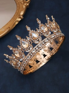 Close-up of golden luxury crown with amber rhinestones on dark blue velvet background