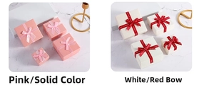 Detail of square pink and white jewelry boxes with silk ribbons and marble background