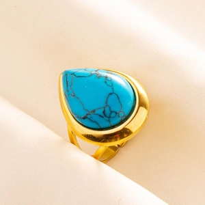 Macro detail of a pear-shaped turquoise stone with black veins on a gold adjustable ring
