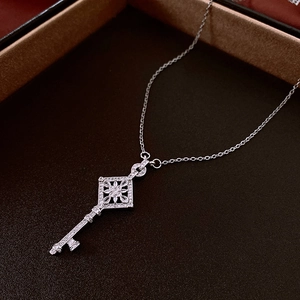 Macro shot of silver diamond flower key pendant with zircon inlays on a fine chain