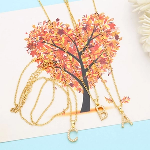 Detail of gold necklaces with faux pearl-encrusted A, B, and C letter pendants