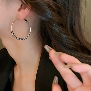 Detail of silver bamboo-joint textured hoop earrings worn by a model for a luxury look