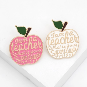 Pink and white enamel apple teacher brooches with golden trim and inspirational text