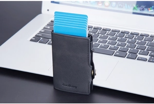 Close-up of black leather RFID pop-up card holder with six cards on a silver laptop
