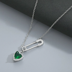 Detailed shot of silver safety pin necklace with heart green zircon and pavé crystals